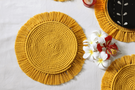 mustard round macrame table mats placed on a table with some flowers