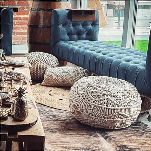 macrame pouffe displayed in a living room with sofa and decorated coffee table